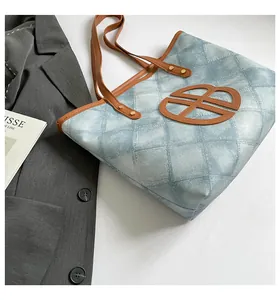 Close-up of blue lattice tote bag with brown leather handles and chic urban style
