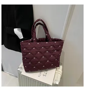 Nahaufnahme der weinroten Stepptasche mit weißem Schleifenprint und Rautensteppmuster