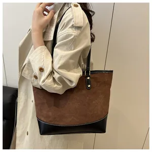 Detail of large brown suede tote with diamond stitching and black leather trim accents