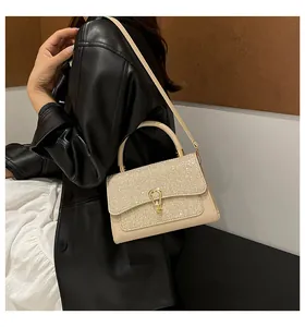 Macro detail of beige leather crossbody bag with glitter flap and golden horseshoe buckle