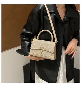 Detail of beige sequin flap bag with golden horseshoe metal buckle and leather handle