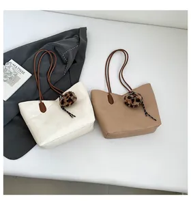 Flat lay of large tote bags in white and khaki with leopard plush charm details
