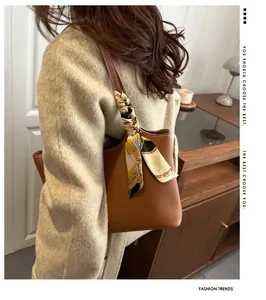 Brown leather tote bag with silk scarf detail worn by model in a minimal setting