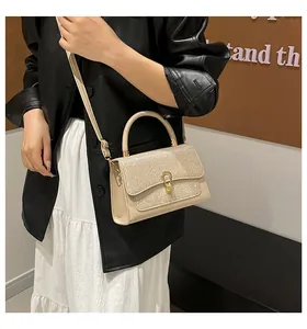 Detail of glitter flap and horseshoe buckle on a modern champagne crossbody bag