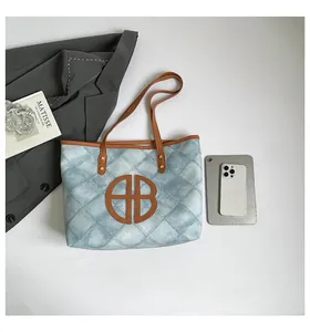 Detailed top view of a large blue quilted tote bag with brown handles and a central logo