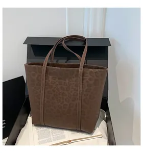 Detailed view of leopard print tote bag with brown faux suede texture and long straps
