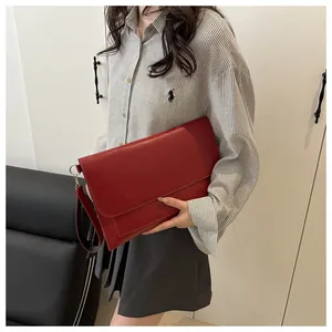 Détail de la pochette enveloppe en cuir rouge avec dragonne dans un décor lifestyle