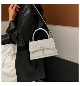 Silver sequin handbag with gold metallic clasp worn by a model in a leather jacket