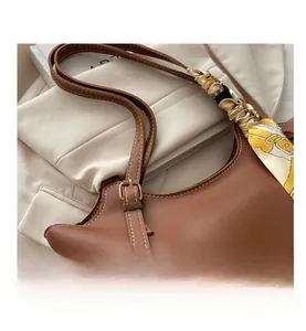 Close-up of brown faux leather tote with white stitching and gold buckle detail