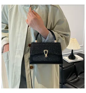 Close-up of black square handbag with glitter flap and golden shield metal buckle