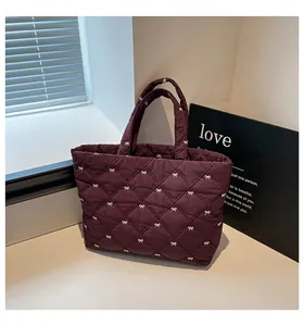 Detailaufnahme des gesteppten Stoffes mit weißen Bogstickereien auf der burgunderroten Tasche