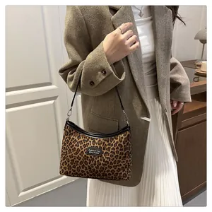 Detail der hobo-tasche mit leopardenmuster getragen mit braunem wollmantel im innenraum