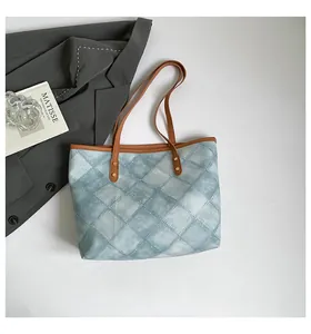 Detail view of light blue quilted tote bag with brown leather straps and metal rivets