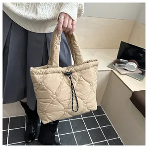 Detail of heart-quilted texture and woven drawstring on the beige tote bag