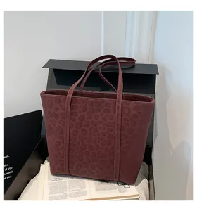Detailed view of burgundy leopard print tote bag with long shoulder straps on a minimalist set