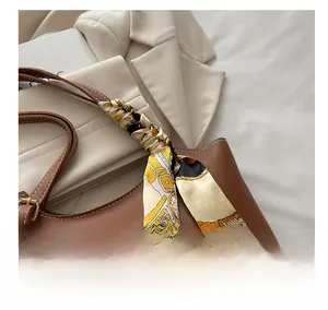 Detail of brown leather tote bag with silk scarf handle and golden hardware buckle