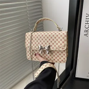 Chic cream crossbody bag with brown geometric print and silver metal bow ornament