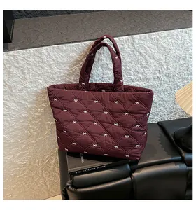 Detail der burgunderroten Stepptasche mit weißem Schleifendruck auf strukturiertem Hintergrund