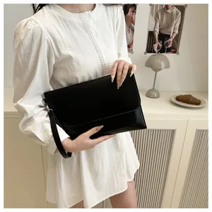 Détail d'une pochette enveloppe chic en cuir noir avec dragonne amovible et fermoir métal