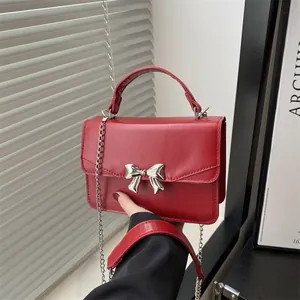 Chic red square crossbody bag featuring a silver metal bow buckle and chain strap