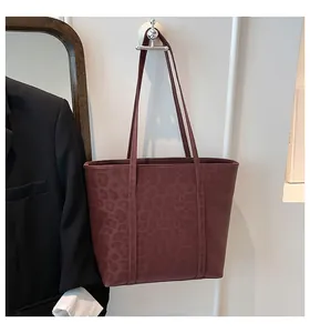 Close-up of a deep burgundy leopard print tote bag hung on a wall in a professional setting