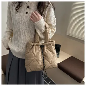 Detail of khaki quilted tote bag featuring heart embroidery and drawstring closure