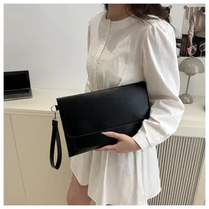 Détail d'une pochette minimaliste en cuir noir avec anneau en D et dragonne amovible