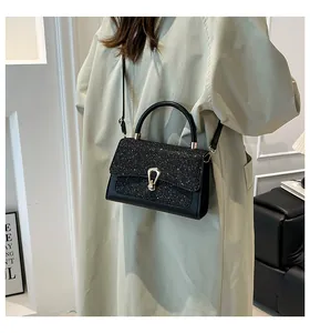 Detail of black sequin square bag with golden U-shaped buckle on a green trench coat