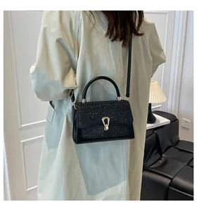 Close-up of black sequin handbag with gold horseshoe buckle on model's shoulder