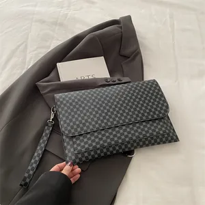Détail macro de la pochette enveloppe à motif géométrique avec dragonne sur costume