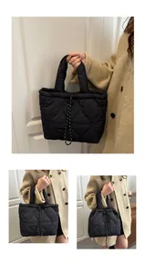 Detail of black quilted tote bag with heart patterns and drawstring closure mechanism