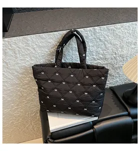Detail einer schwarzen Stepptasche mit weißen Bogenschleifen-Stickereien und Textur