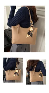 Detail view of khaki tote bag with a patterned silk scarf wrapped around the handle