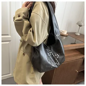 Dettaglio borsa tote in pelle nera con borchie argentate che formano una stella