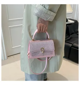 Detail of light pink crossbody bag with textured flap and elegant gold U-shaped buckle