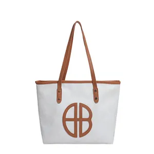 Minimalist white tote bag with brown straps and circular geometric patchwork design
