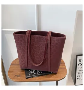 Detail of burgundy leopard embossed tote bag on a wooden table in home setting