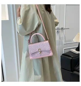 Detail of light pink crossbody bag with shimmering sequins and gold horseshoe buckle