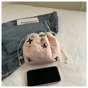 Pink quilted drawstring pouch with black embroidered bows and soft texture detail