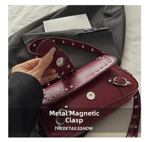 Macro detail of silver magnetic snap closure on wine red studded leather shoulder bag