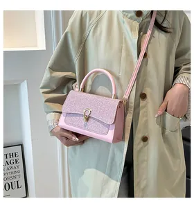 Detail of pink shoulder bag with woven texture flap and golden metal clasp on light coat