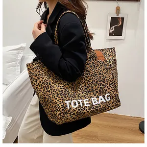 Detailed shot of large leopard print tote bag with black strap and white text logo