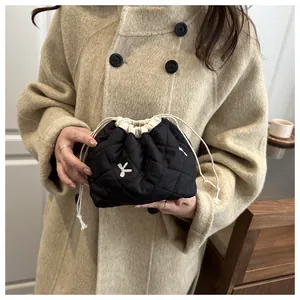 Close-up of black quilted drawstring bucket bag with silver K-logo and bow detail