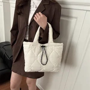 White heart quilted tote bag with black drawstring detail held by a model in casual wear