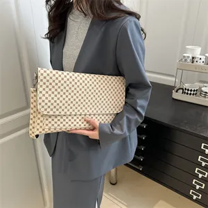 Pochette enveloppe beige avec motifs géométriques et dragonne pour un style chic