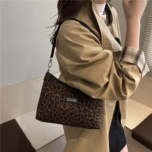 Schicke Vintage Umhängetasche mit Leopardenmuster und schwarzem Riemen am Model im Trenchcoat