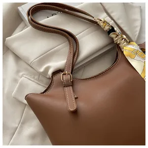 Detail of brown tote bag with white stitching and decorative silk scarf on strap
