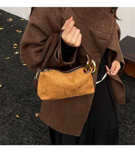Detailed close-up of retro suede pillow bag featuring gold metal rings and leather handles