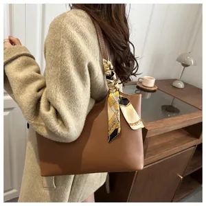 Side view of a large brown leather tote bag with silk scarf on model's shoulder