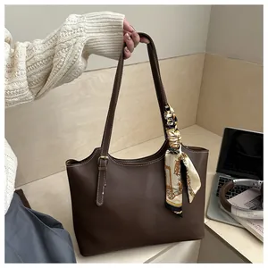 Close-up of dark brown tote bag with white contrast stitching and a floral silk scarf